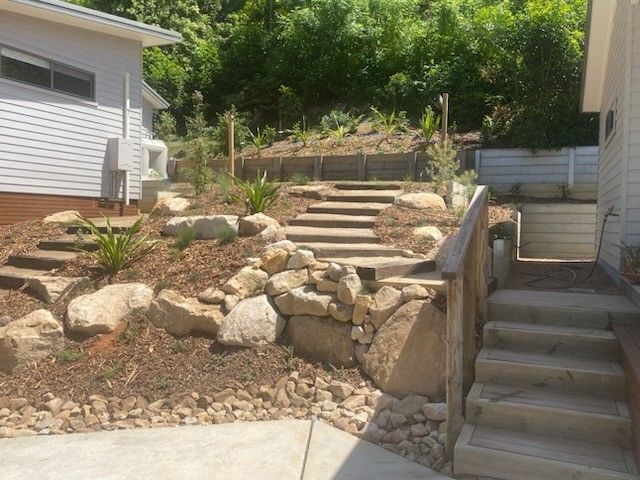 Construction site with a two-story house. Wooden framework for a deck or awning in progress. A black dog is present.