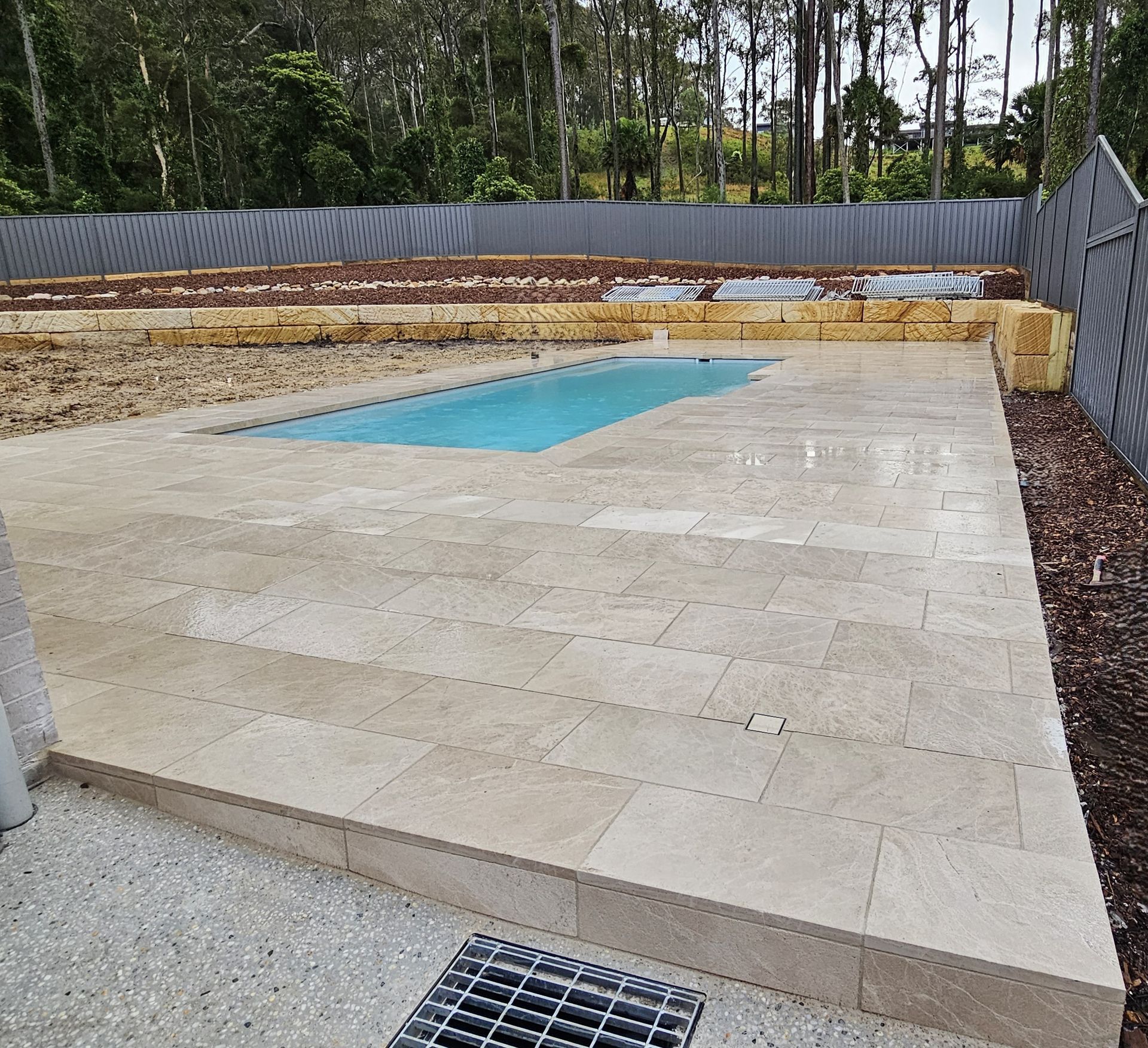 Crane lifting steel beam over construction site; workers guide it into place.