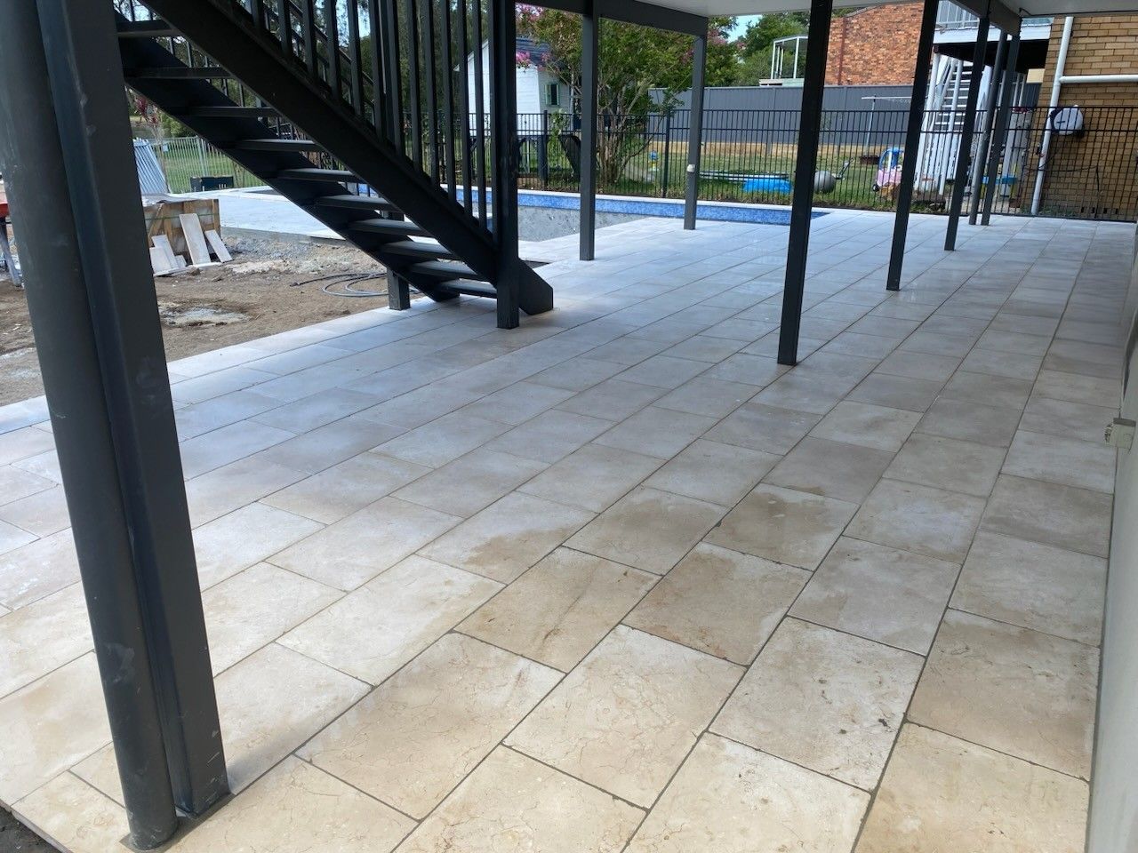 Path to home with plants, brick building, and dark gray driveway.