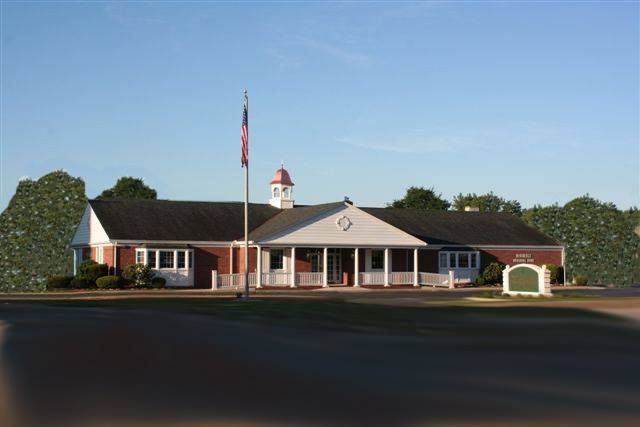 Brick building with white trim and American flag, green sign.