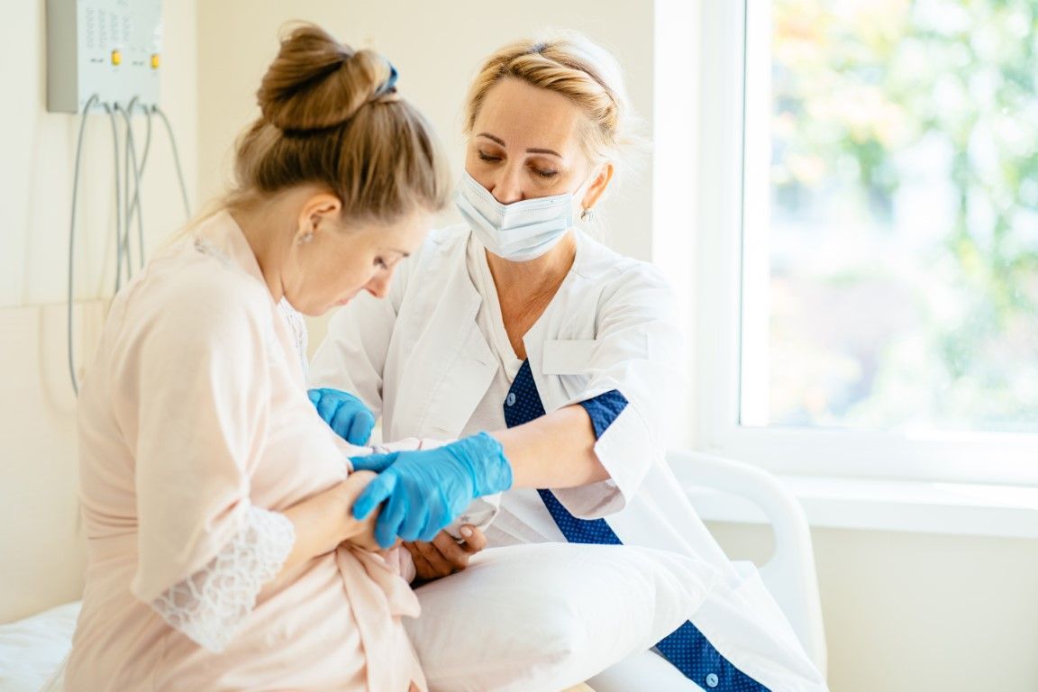 A pregnant woman is sitting in a hospital bed while a nurse examines her belly.