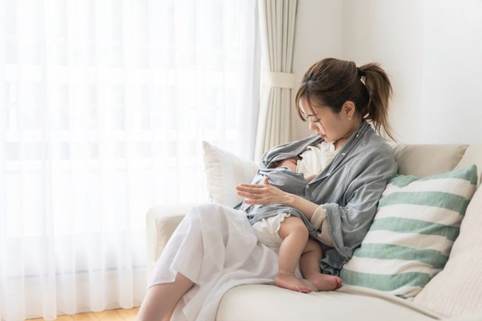A woman is sitting on a couch holding a baby.