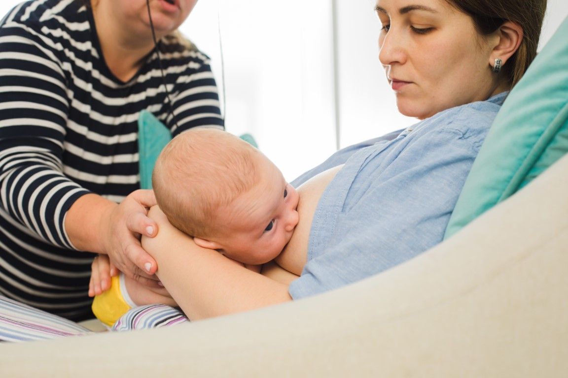 A woman is breastfeeding a baby in a hospital bed.