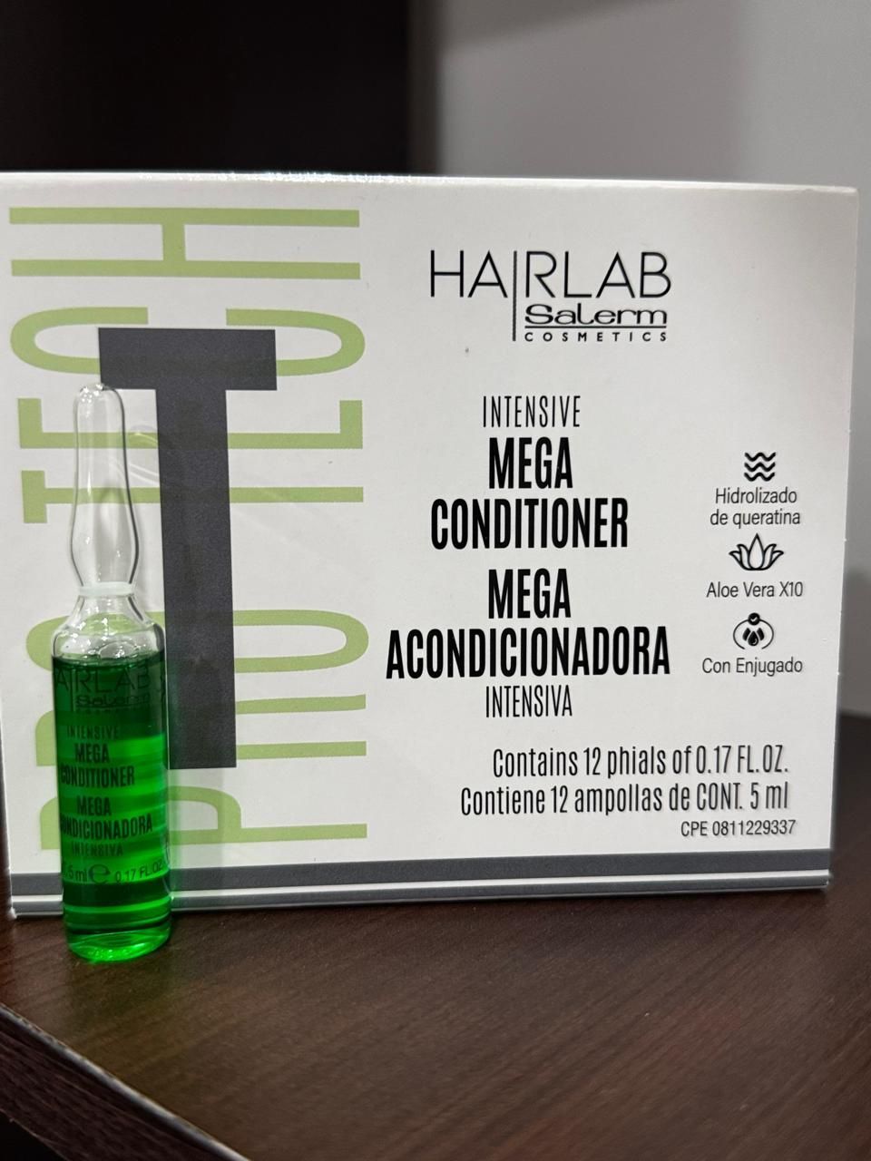 Una caja de mega acondicionador con una botella verde al lado.
