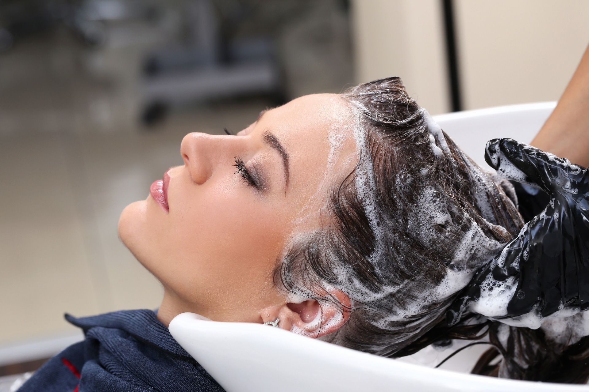 Una mujer se lava el cabello en un lavabo de una peluquería.