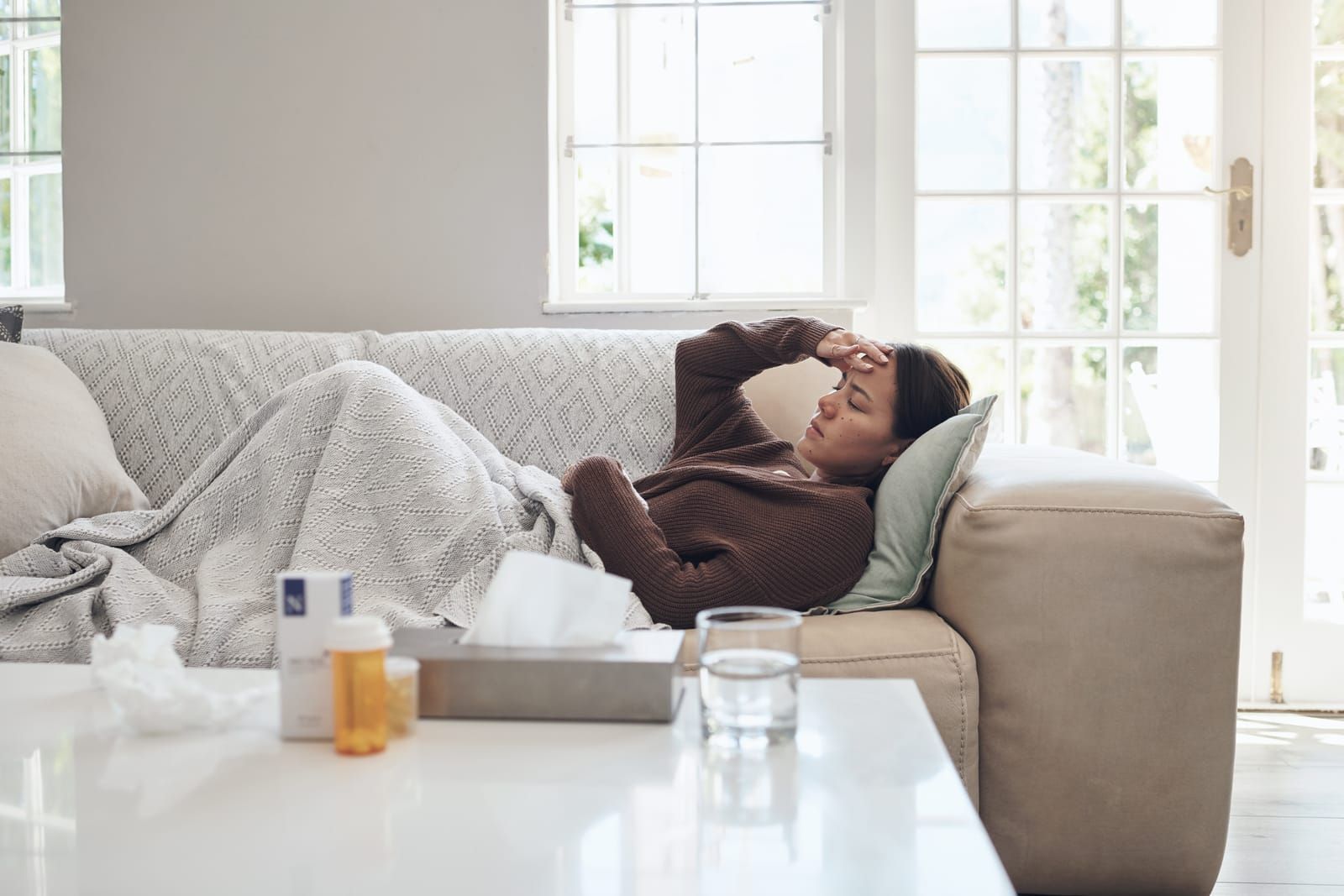 woman-sick-with-headache-with-medication-on-sofa-in-living-room-at-home-tired