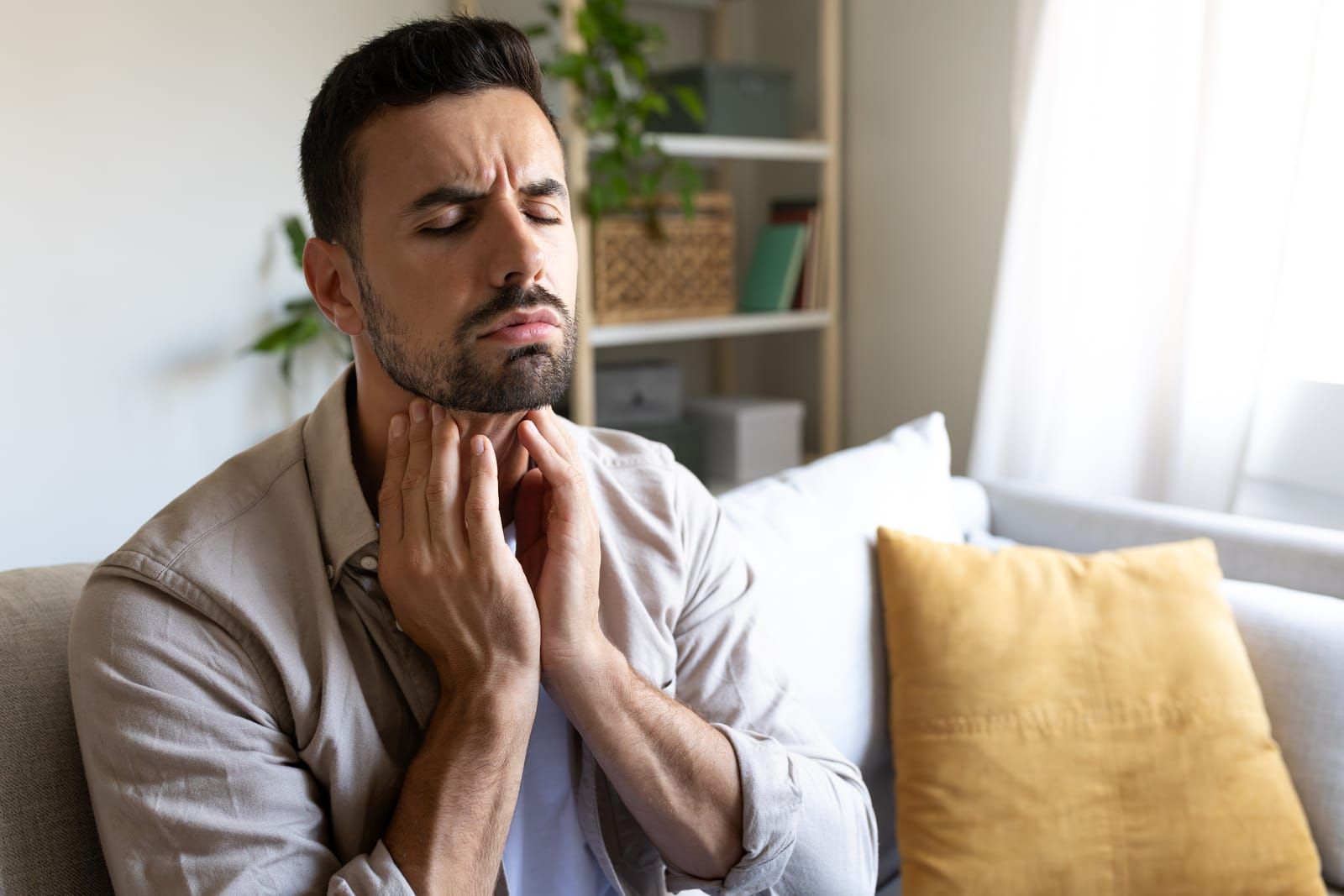 Man suffering from sore throat touching neck feeling pain