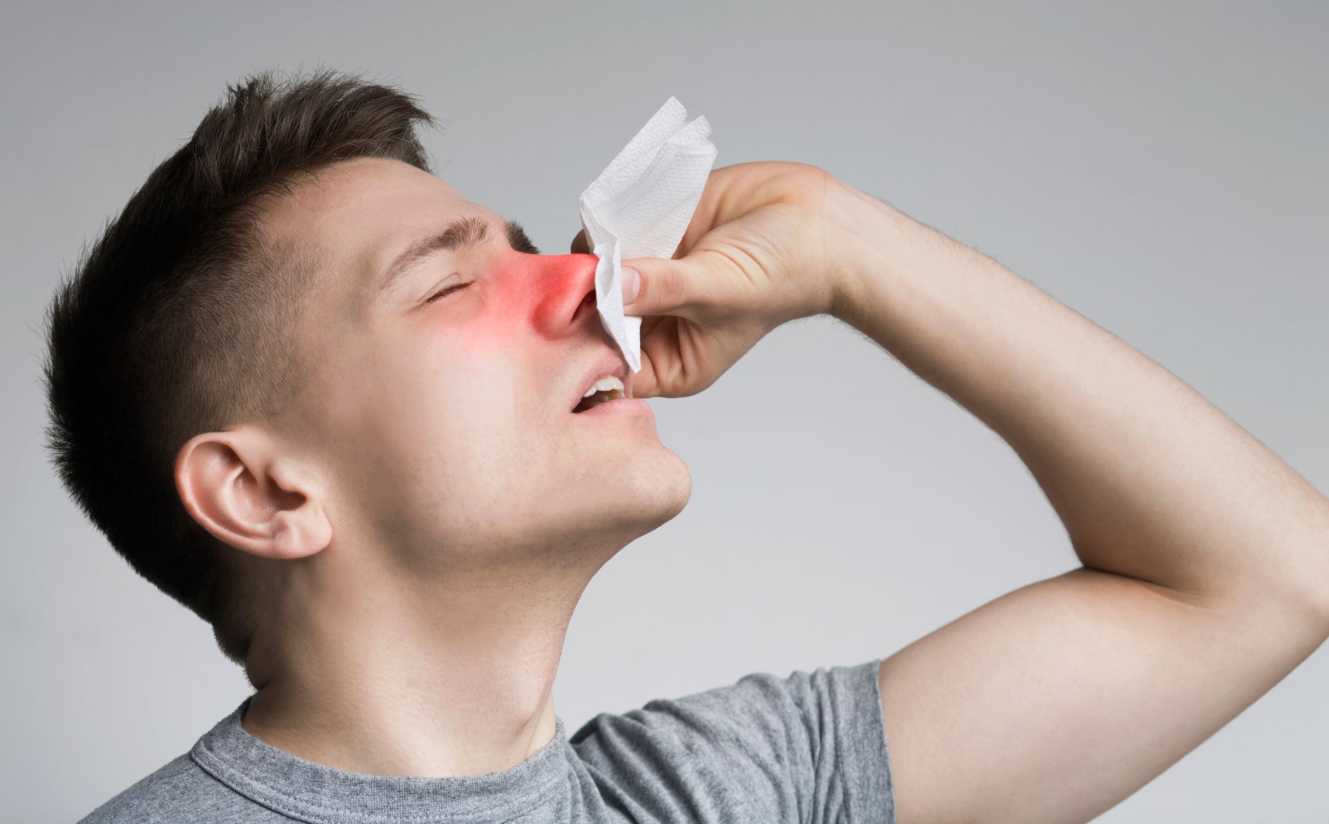 A man with a developed nasal polyps  is blowing his nose with a napkin.
