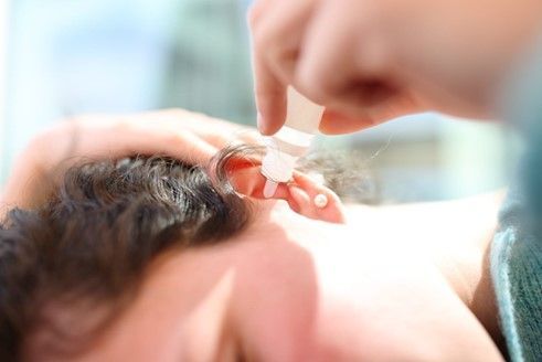 A woman cleaning her ears with peroxide drops