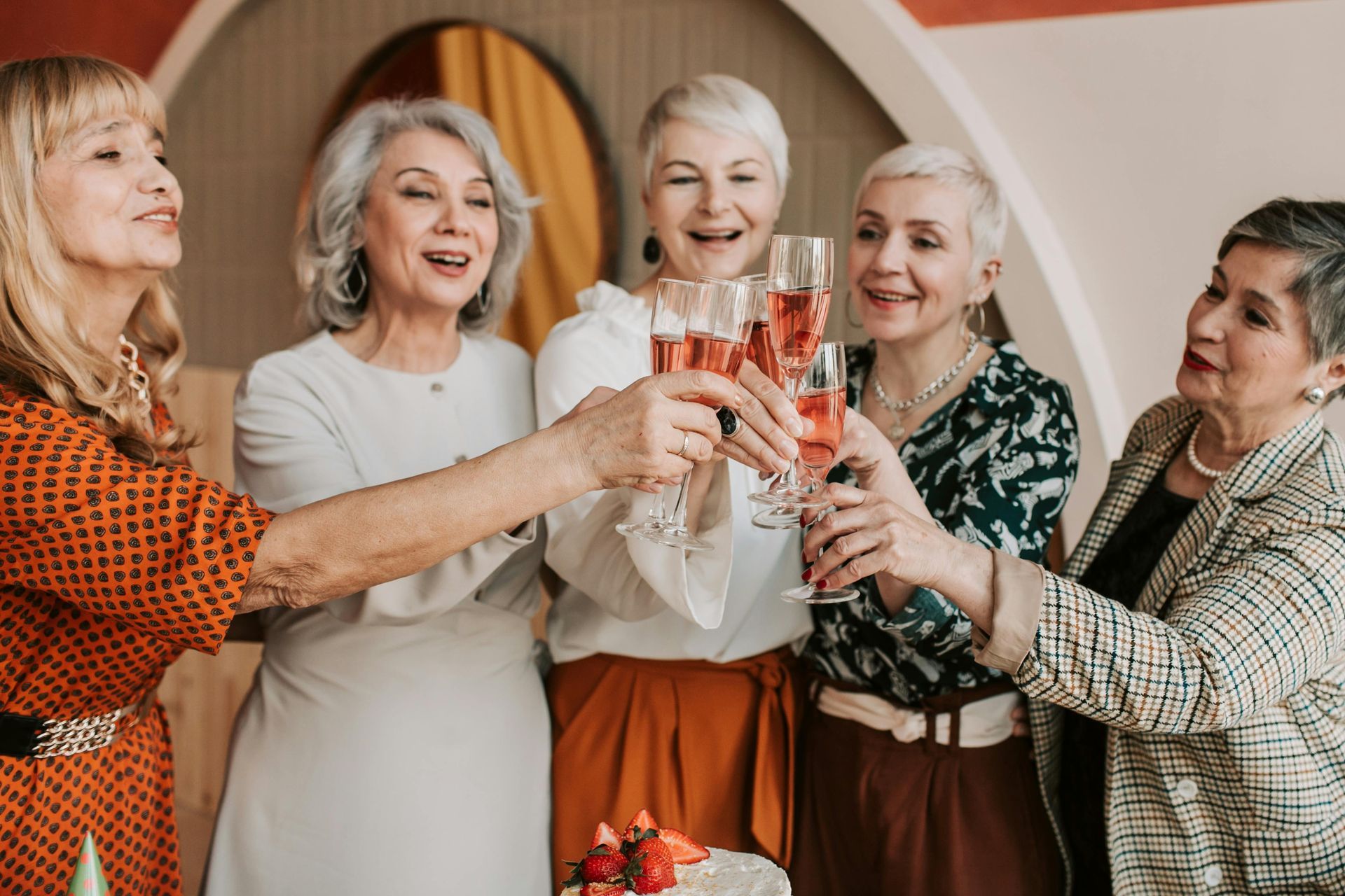 A group of older women are toasting with champagne glasses.