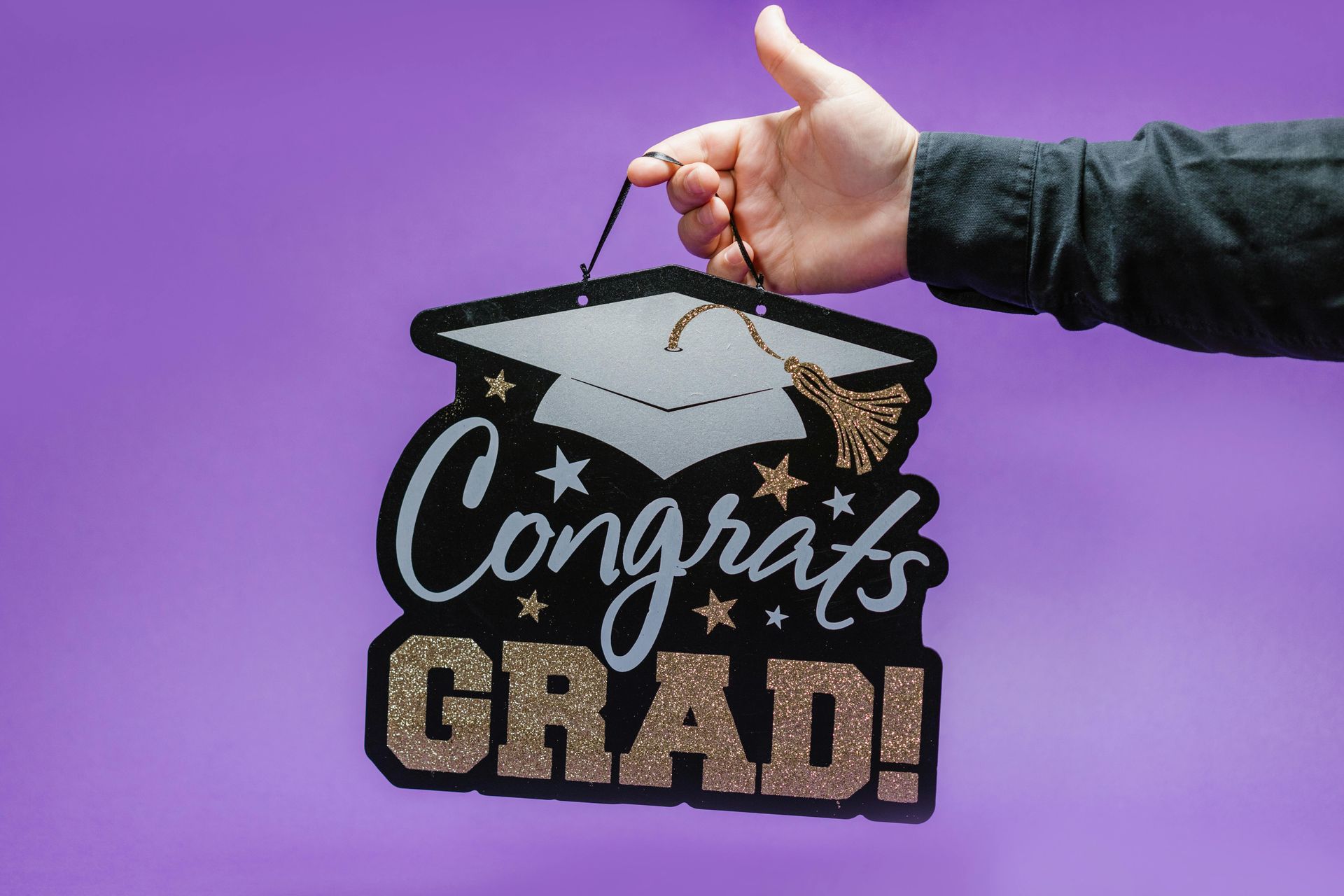 A person is holding a sign that says `` congrats grad ''.