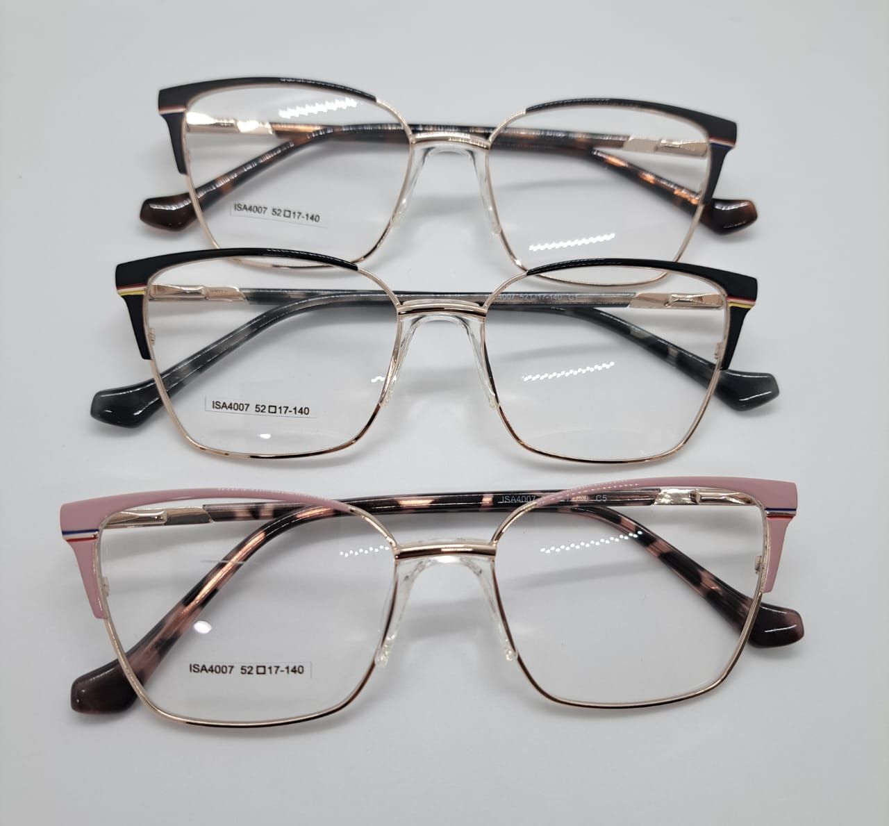 Tres pares de anteojos con marcos dorados y tapas de diferentes colores: negro, negro/carey y rosa/carey.