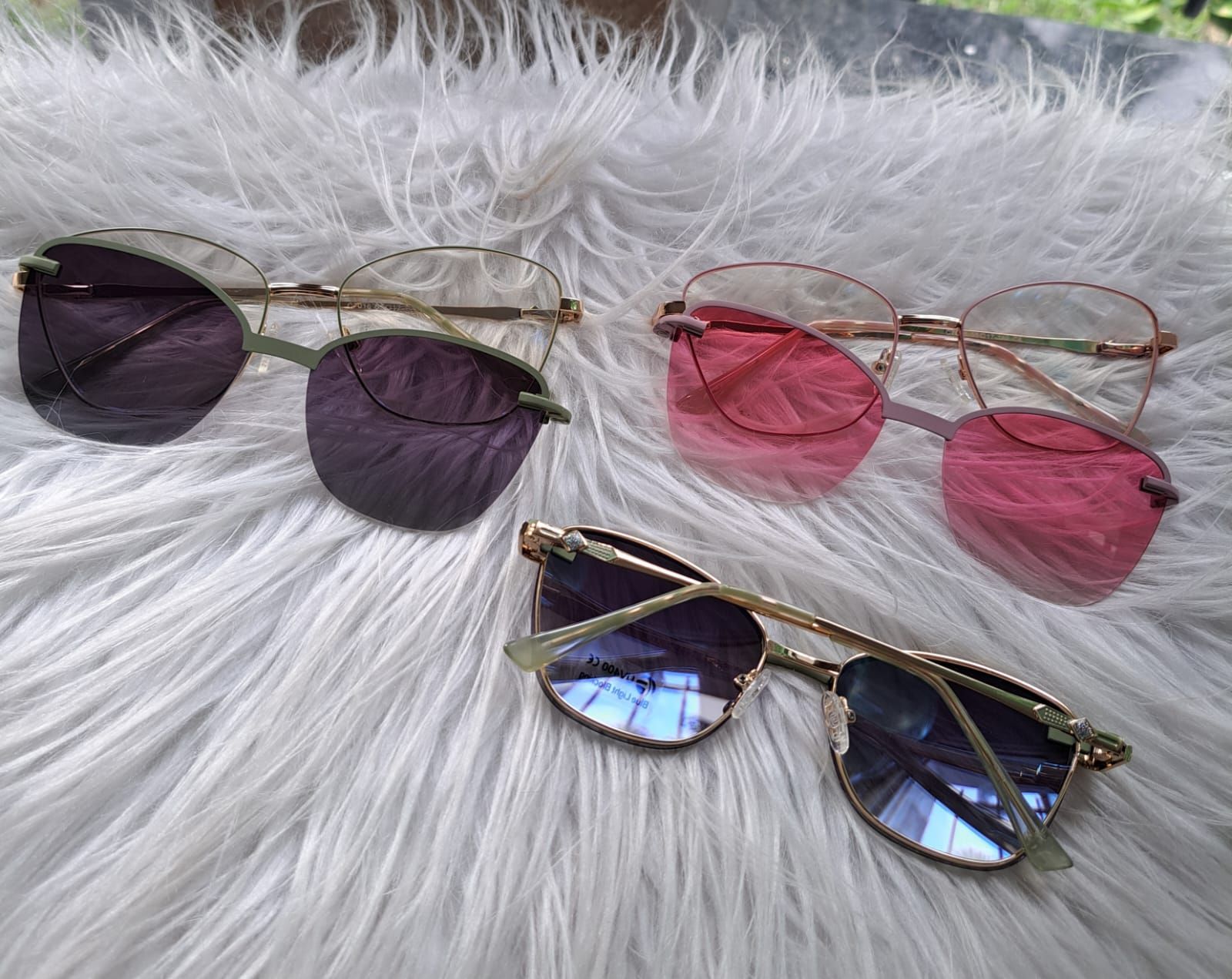 Tres pares de gafas de sol sin montura con lentes tintadas sobre una superficie blanca y esponjosa.