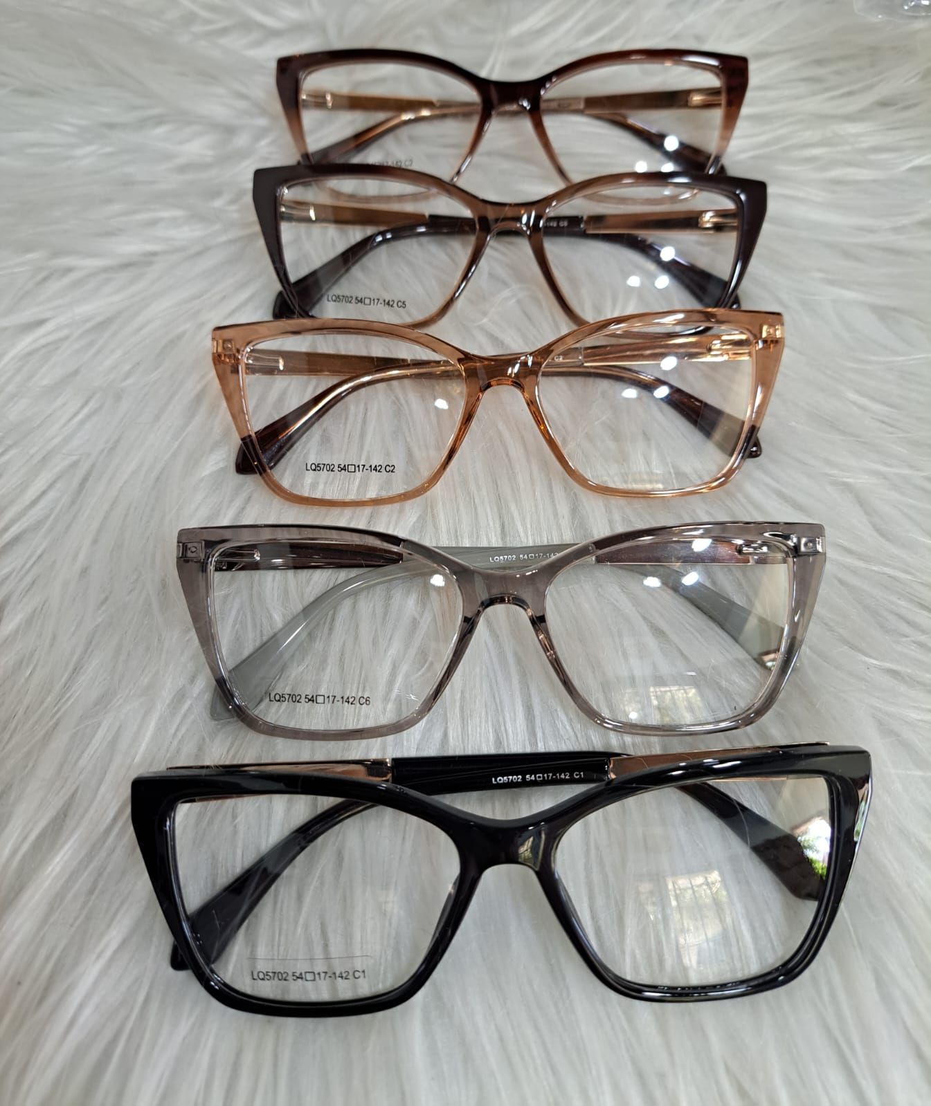 Cinco pares de gafas, de varios colores, dispuestas sobre una superficie blanca y esponjosa.