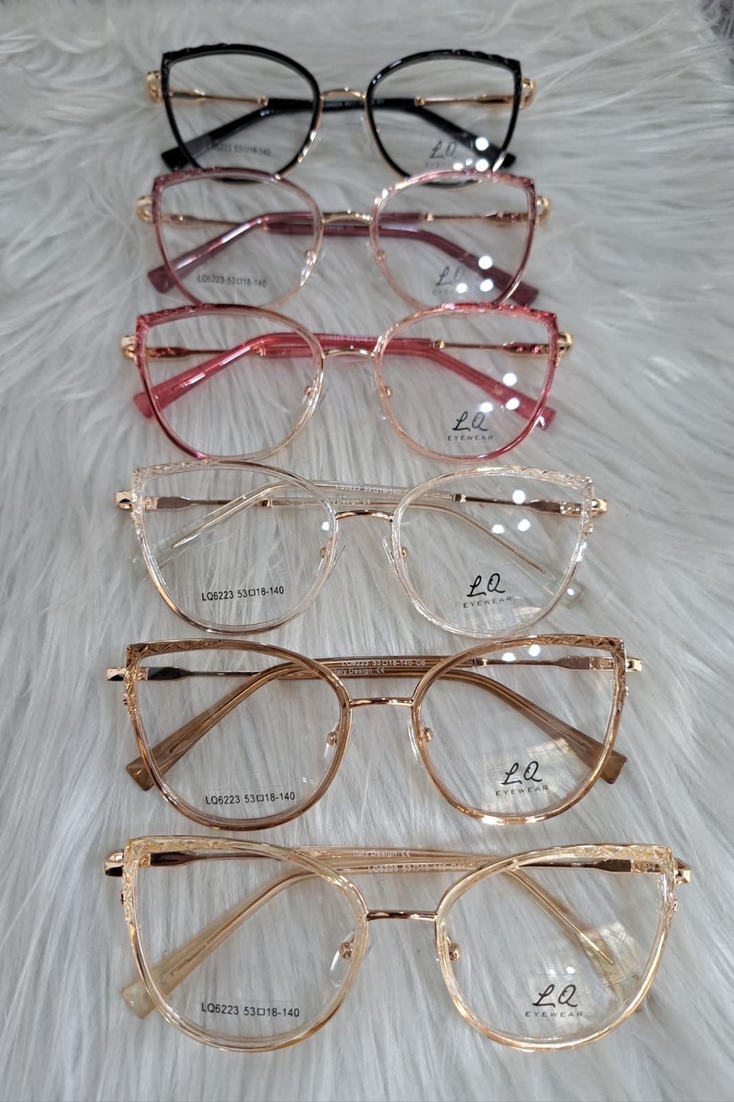 Monturas de gafas en varios colores, dispuestas sobre una superficie blanca y esponjosa.