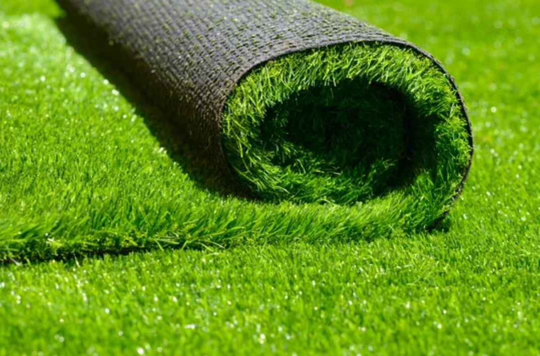 White and purple gloves resting on vibrant artificial grass.