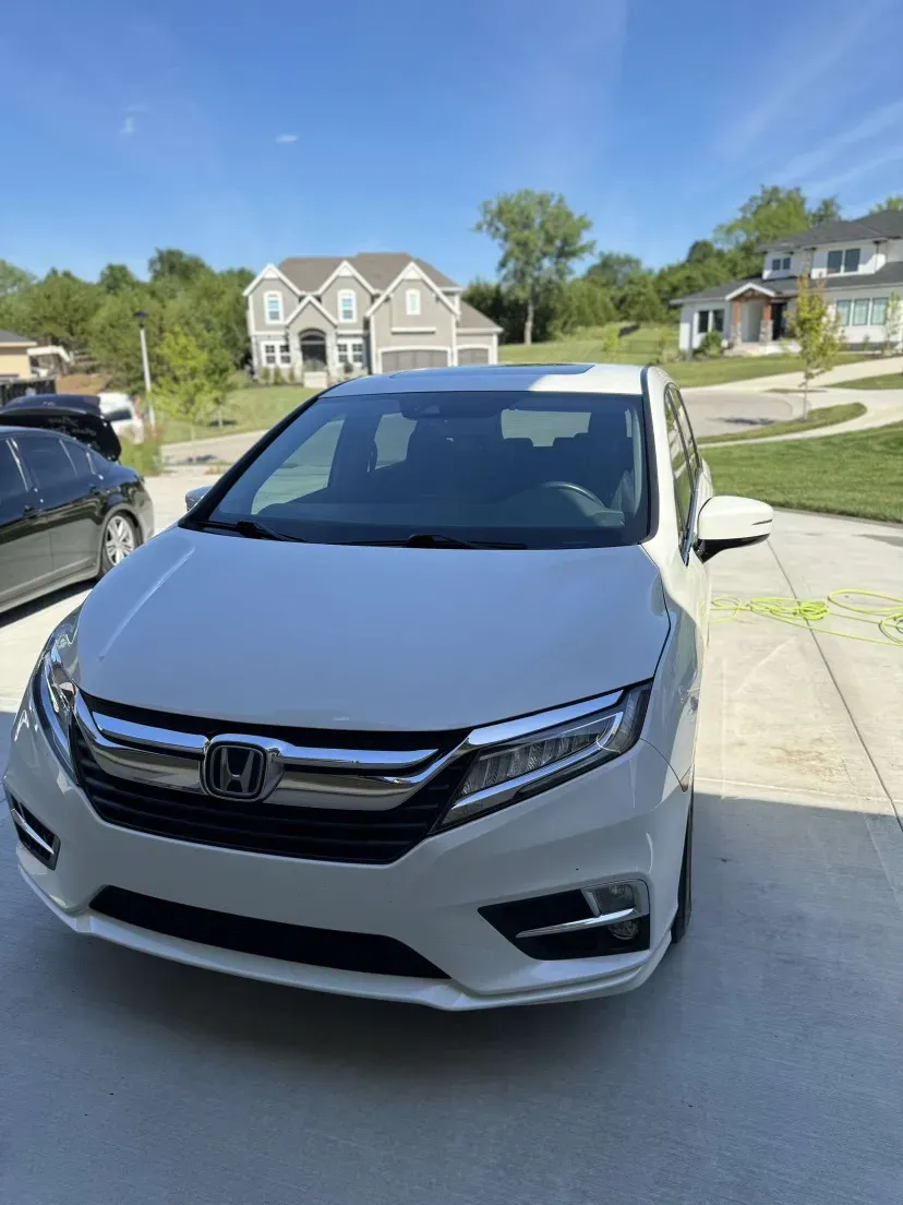 A white honda van is parked in a driveway