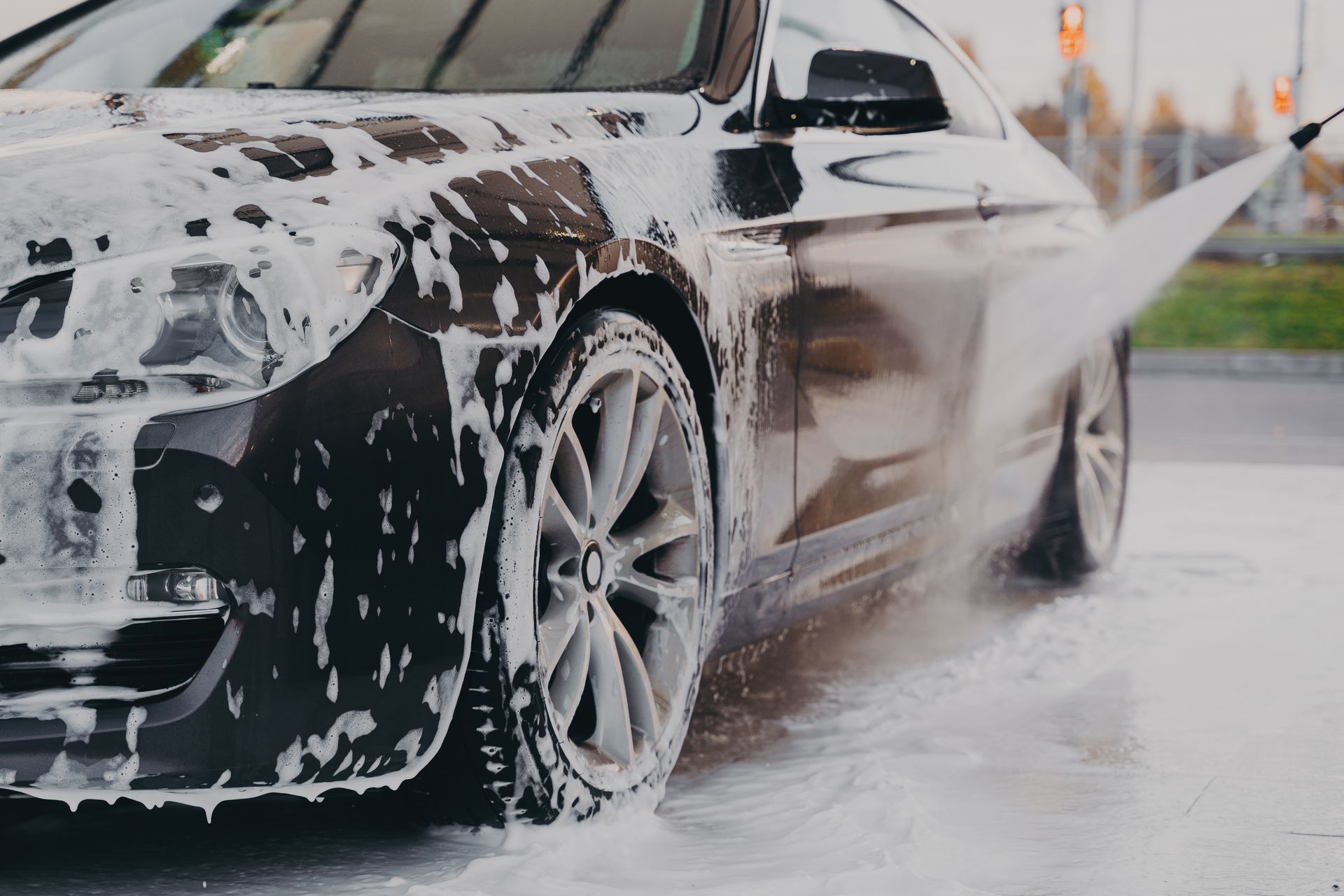This photo shows the exterior of a car being sprayed with a pressure washer. 