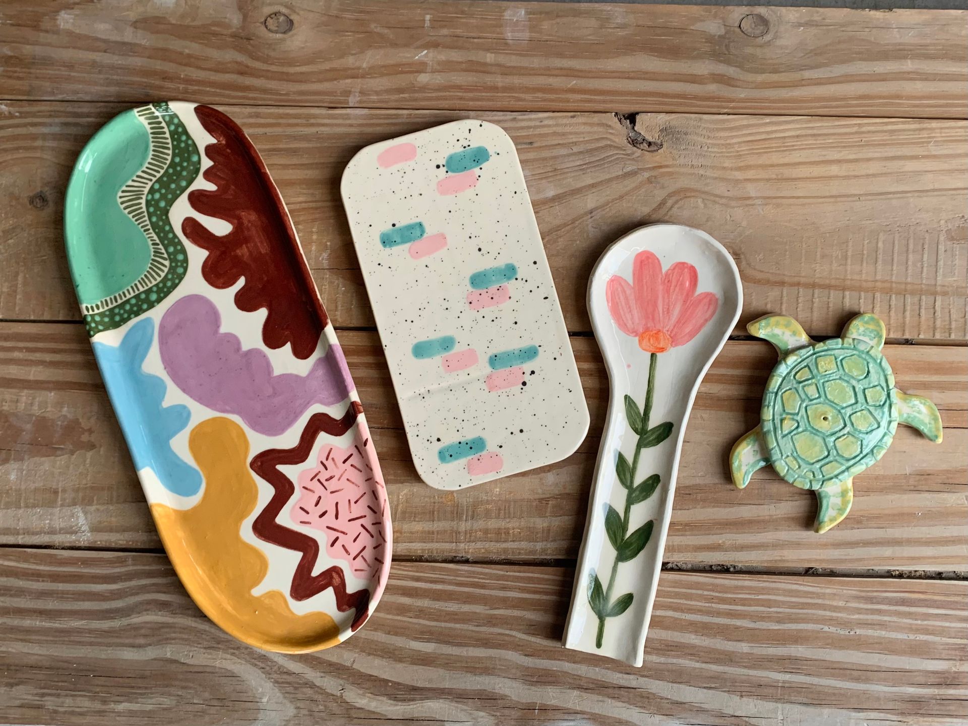 Platos para servir de cerámica de colores y soporte para cuchara sobre una superficie de madera.