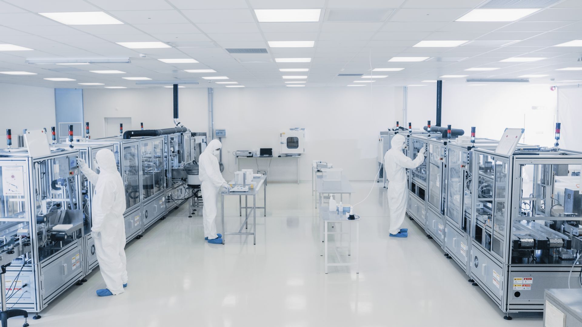 A group of people are working in a clean room in a factory.