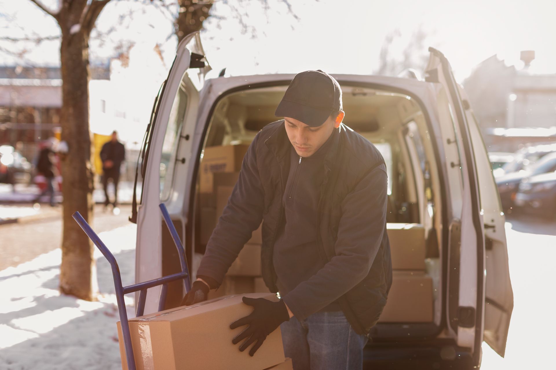 A delivery man is loading a cardboard box into the back of a van.