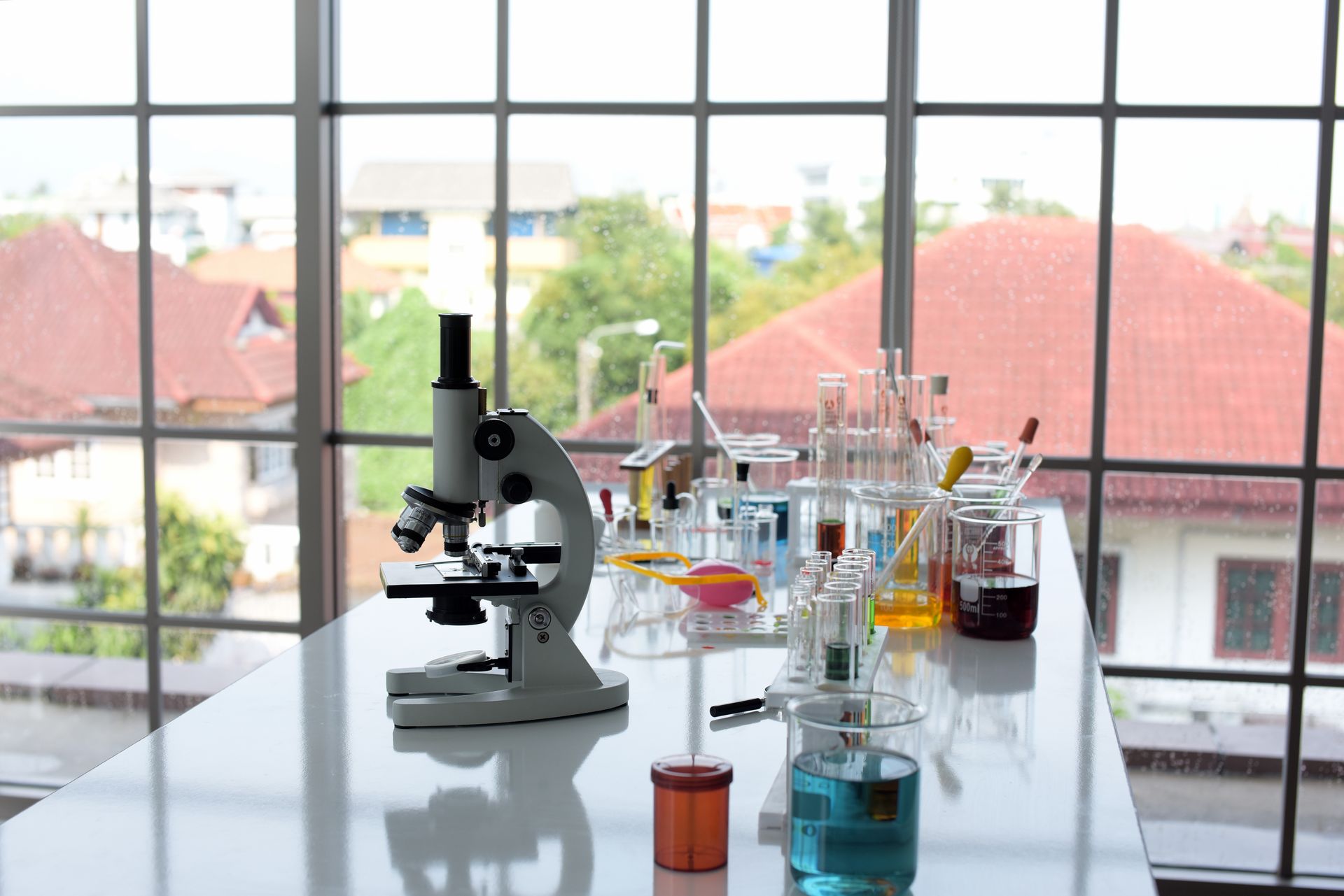 A microscope is sitting on a table in a laboratory next to a window.