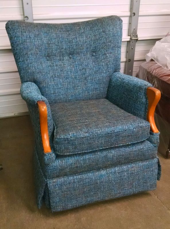 A blue chair with wooden armrests is sitting on a carpet.