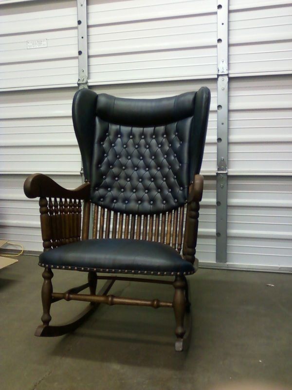 A black rocking chair is sitting in front of a garage door