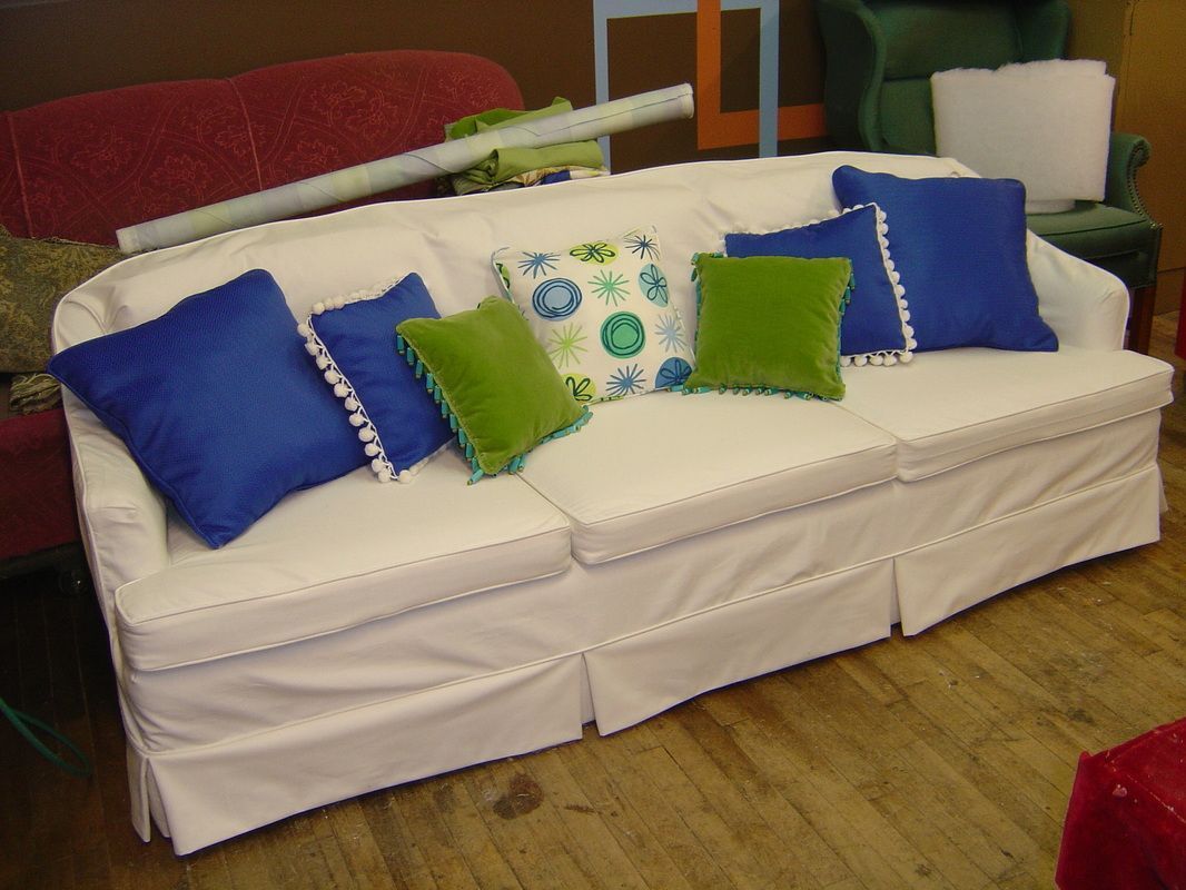 A white couch with blue and green pillows on it