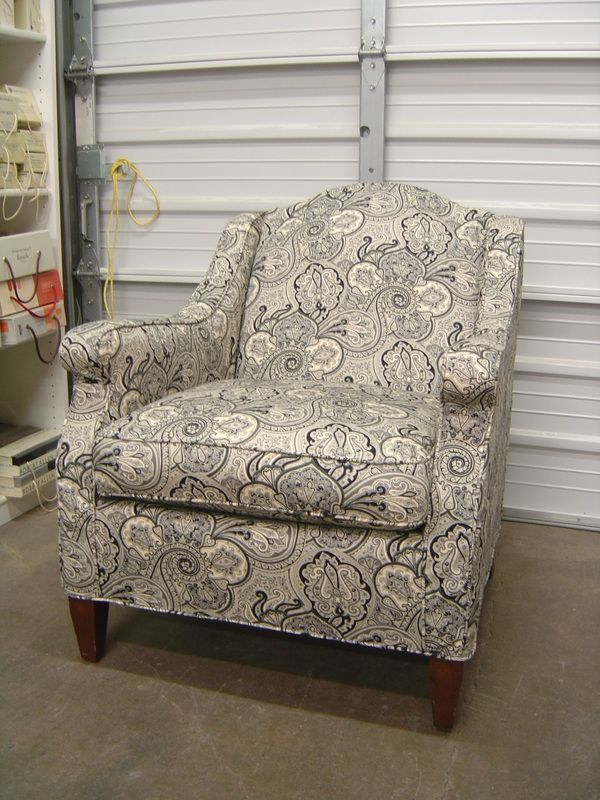 A chair with a floral pattern is sitting in front of a garage door.