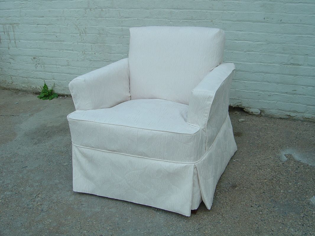 A white chair is sitting in front of a white brick wall.