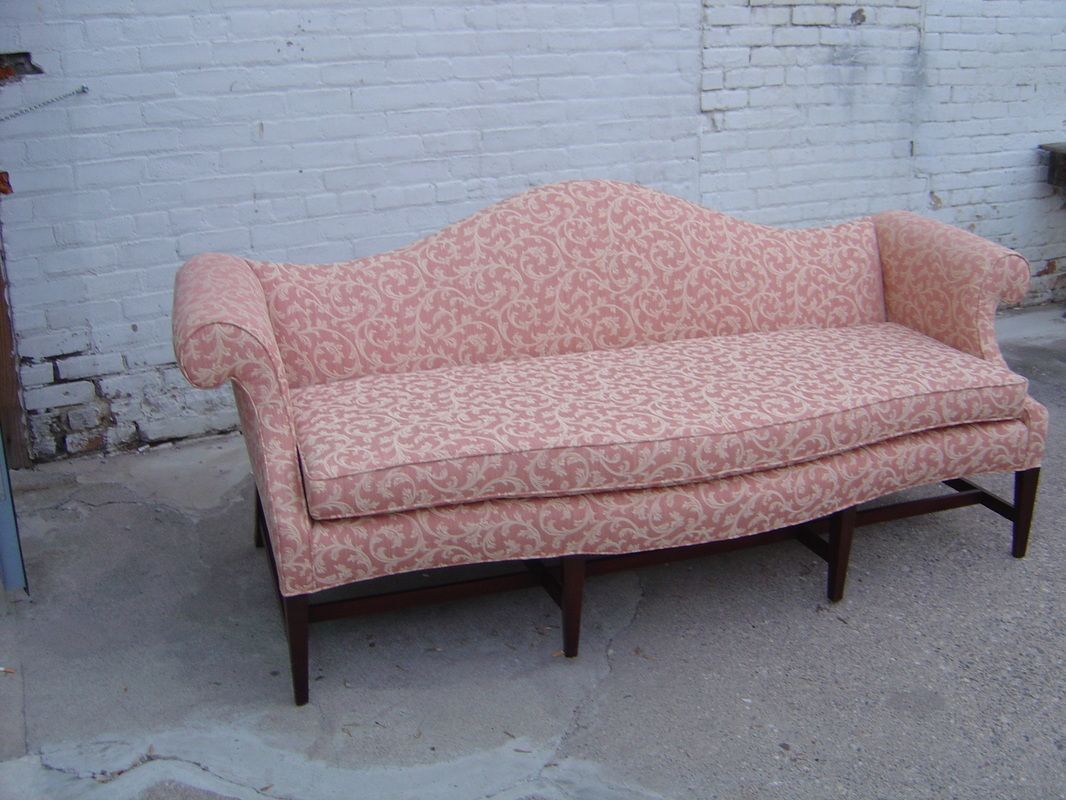A pink couch is sitting in front of a white brick wall.