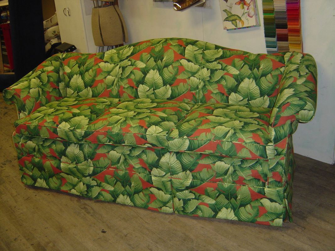 A green and red couch with leaves on it