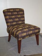 A chair with a striped fabric and wooden legs is sitting on a table.