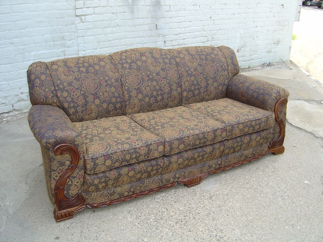 A brown couch is sitting in front of a white brick wall.