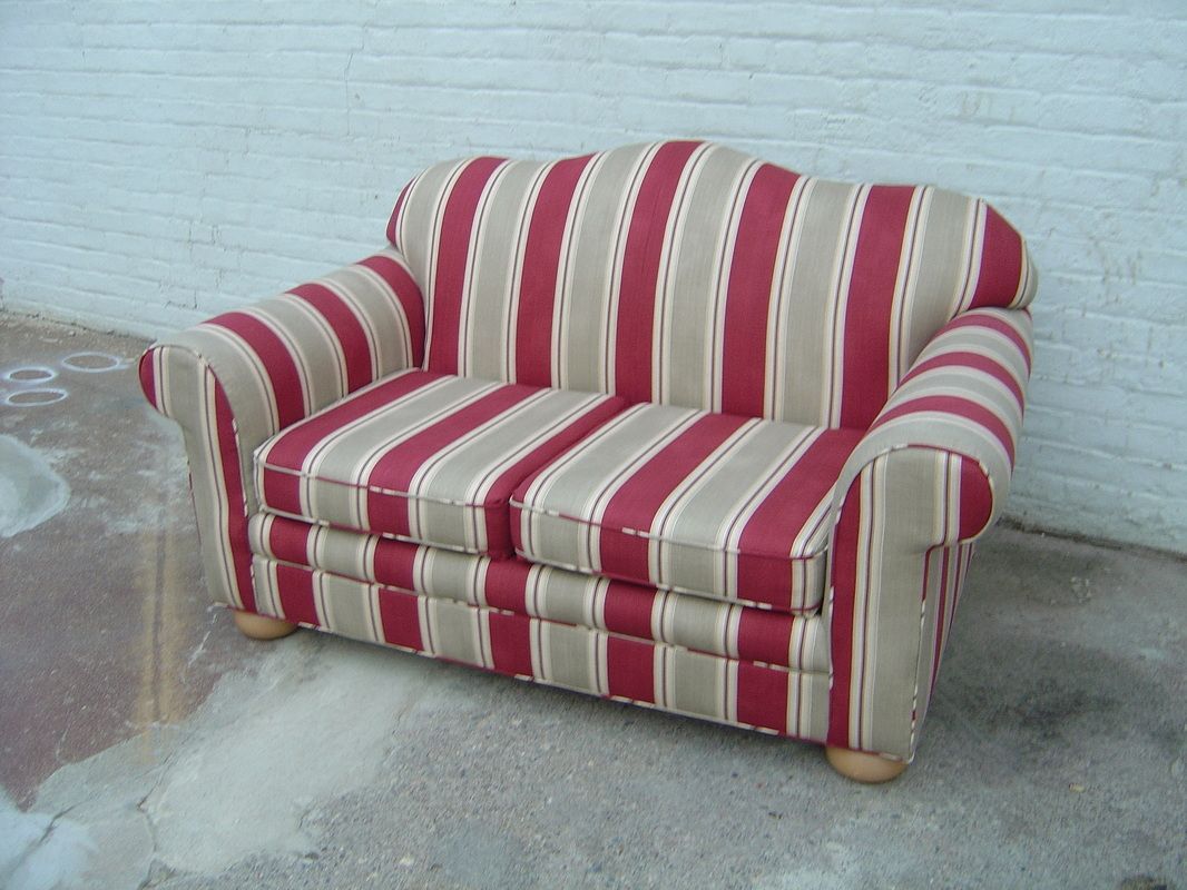 A red and white striped couch is sitting in front of a white brick wall