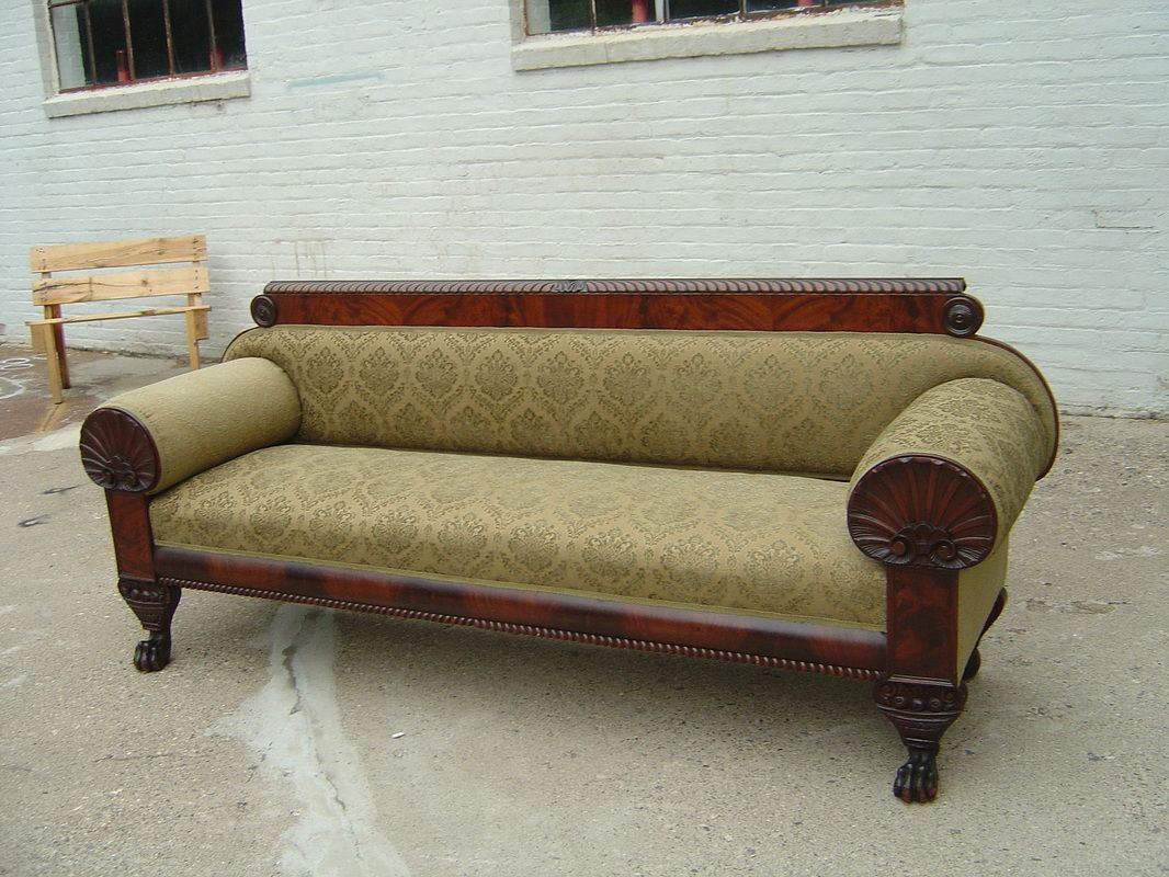 A couch is sitting in front of a white brick wall