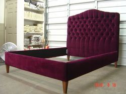 A purple bed with a tufted headboard is sitting in a garage.