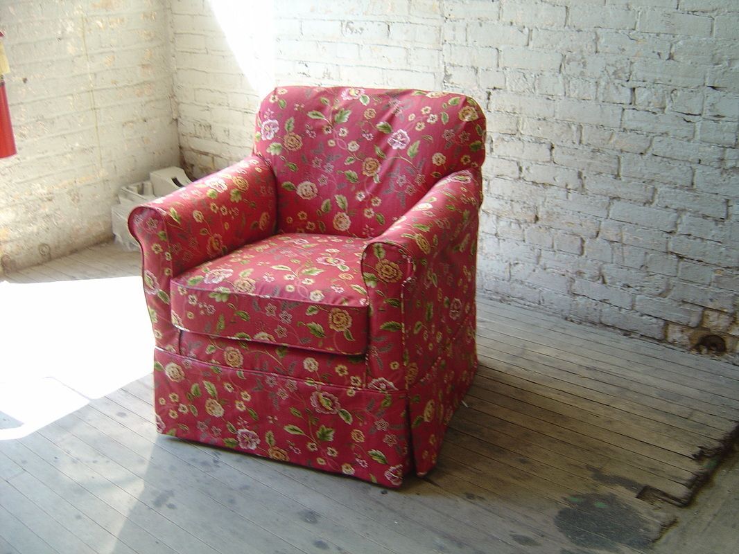 A red chair is sitting in a room with a white brick wall.