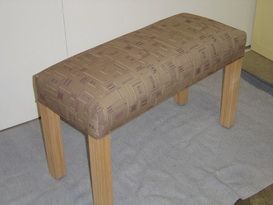 A brown bench with wooden legs is sitting on the floor.