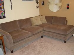 A living room with a sectional couch and ottoman.