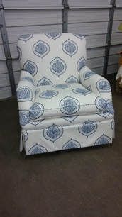 A chair with a blue and white pattern on it is sitting in a garage.