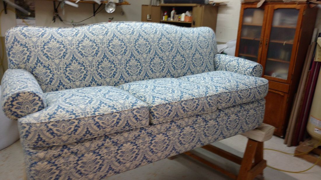 A blue and white couch is sitting on a wooden table in a room.