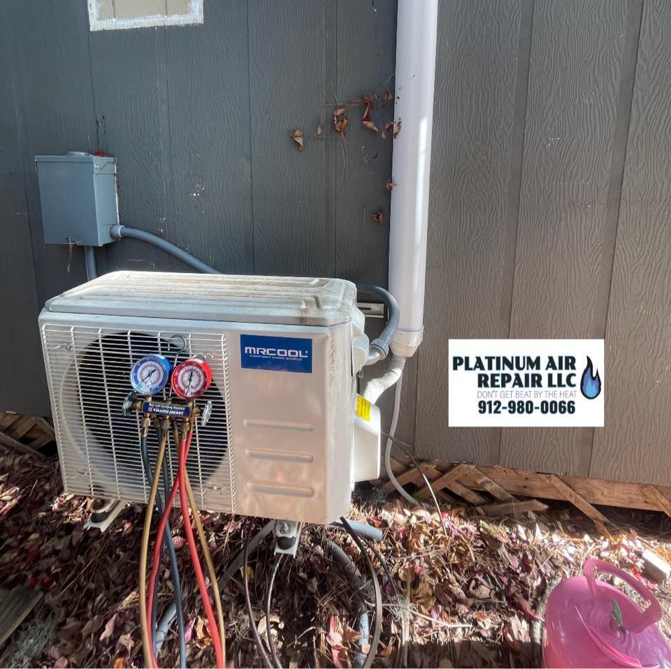 An air conditioning unit being serviced outdoors, with gauges attached.