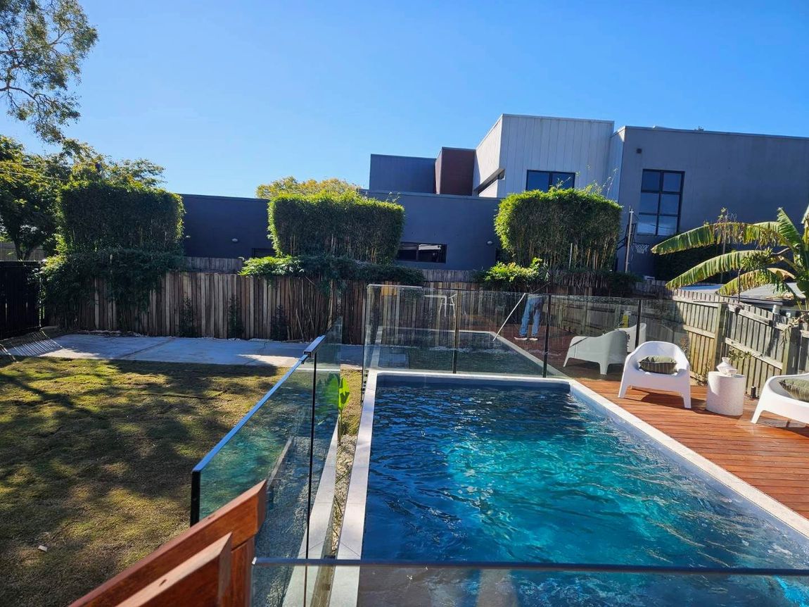 There is a large swimming pool in the backyard of a house.
