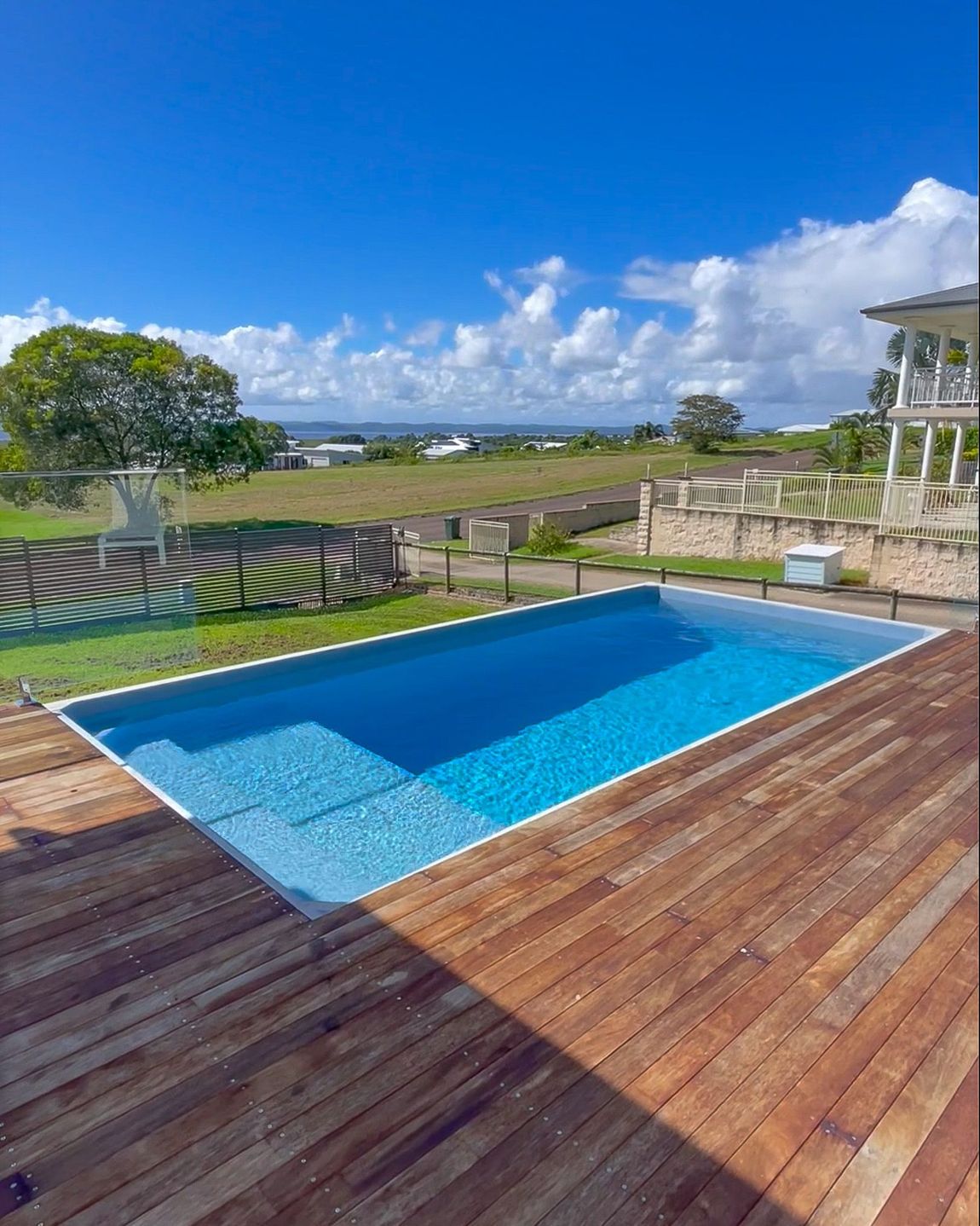 A large swimming pool is sitting on top of a wooden deck.