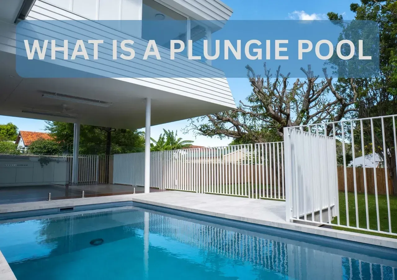 A plunge pool is surrounded by a white fence in front of a house.