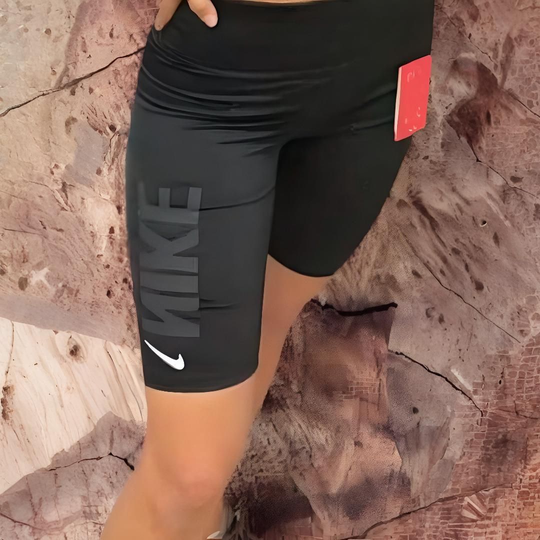Pantalones cortos deportivos Nike negros con logotipo y etiqueta roja, usados ​​por una persona.