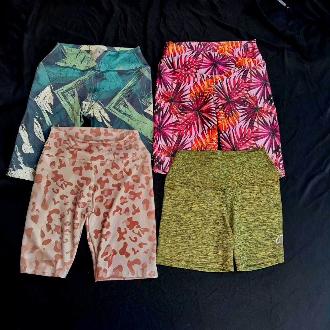 Cuatro pares de pantalones cortos deportivos coloridos sobre una superficie negra; patrones florales y abstractos.