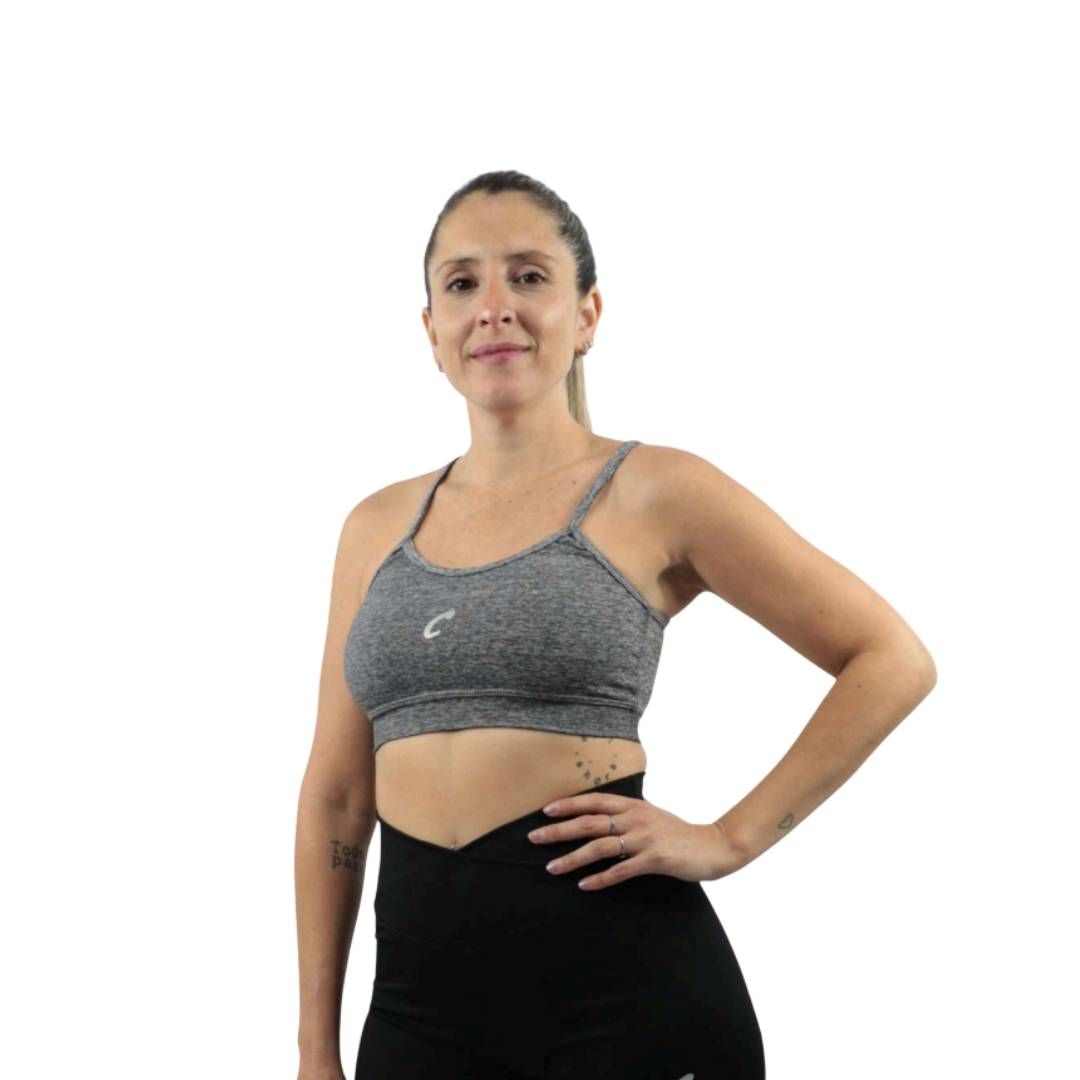 Cuatro sujetadores deportivos en verde azulado, rosa, gris y negro sobre una superficie negra.